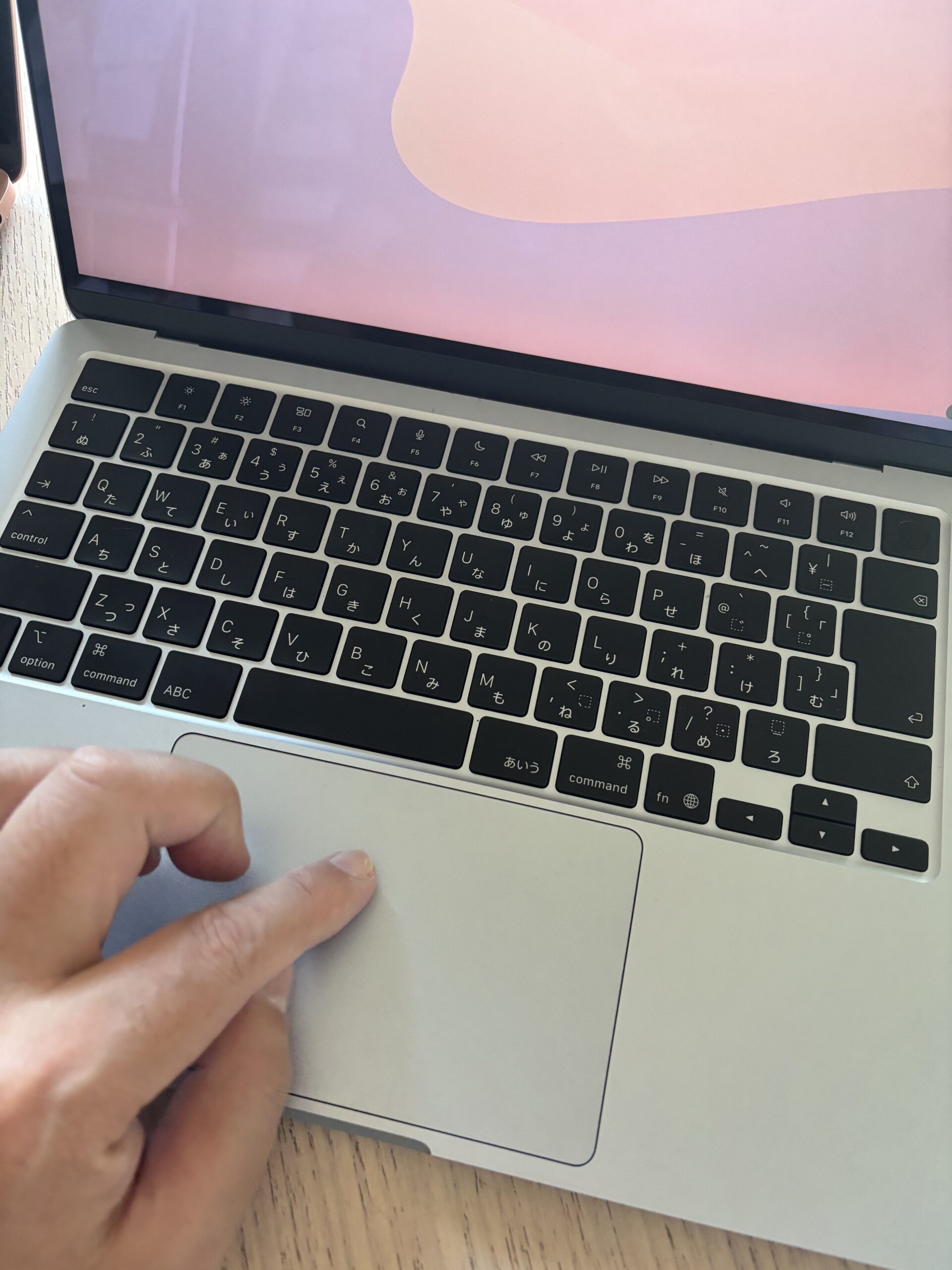 MacBookのトラックパッドを指で直感的に操作している手元の様子